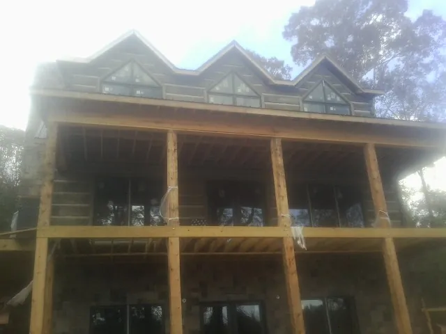 Dormers and porch framing on a large log home under construction — Roof Coating work by our crew in Massena