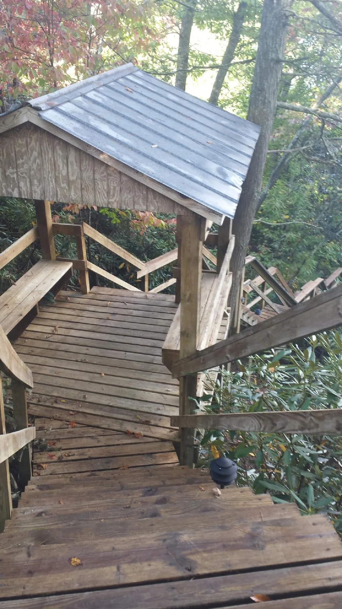 Metal roofed shelter over wooden steps on a wooded walkway — Skylight Repair & Installation work by our crew in Massena