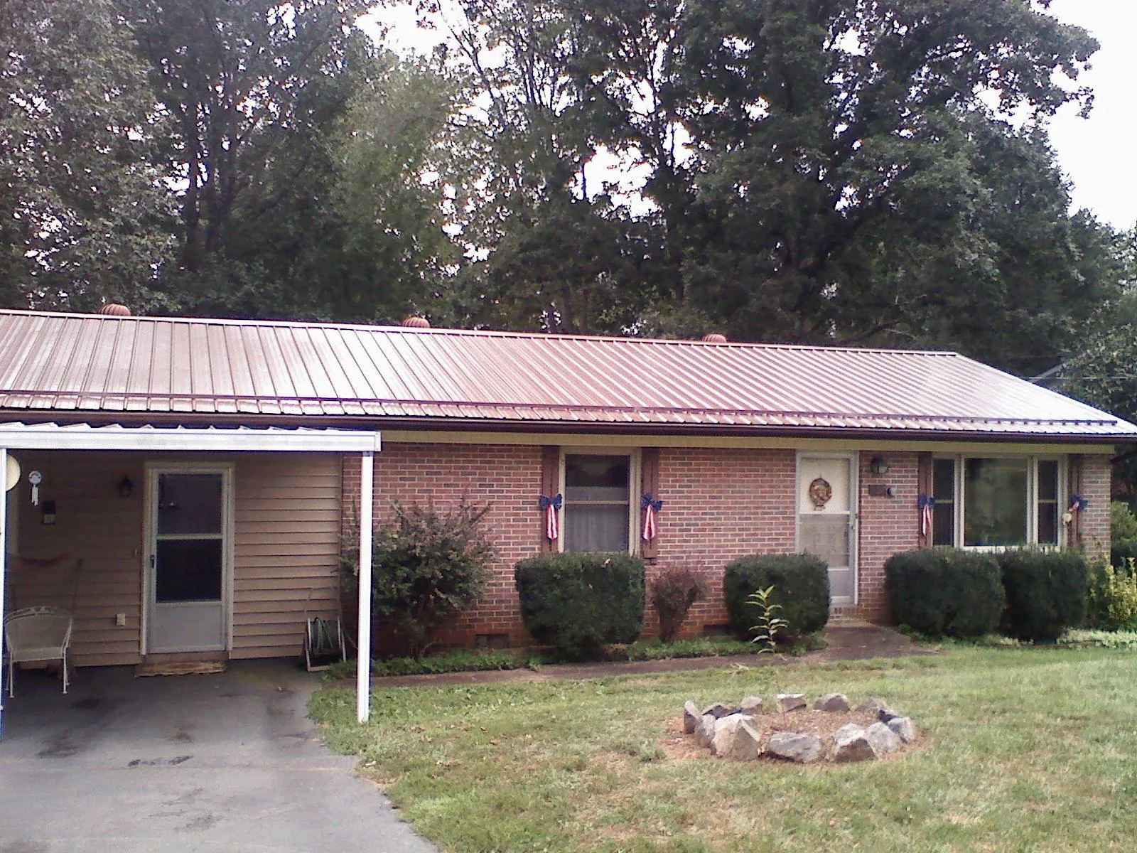 Bronze metal roof and carport on a brick ranch home — Roof Repair work by our crew in Massena